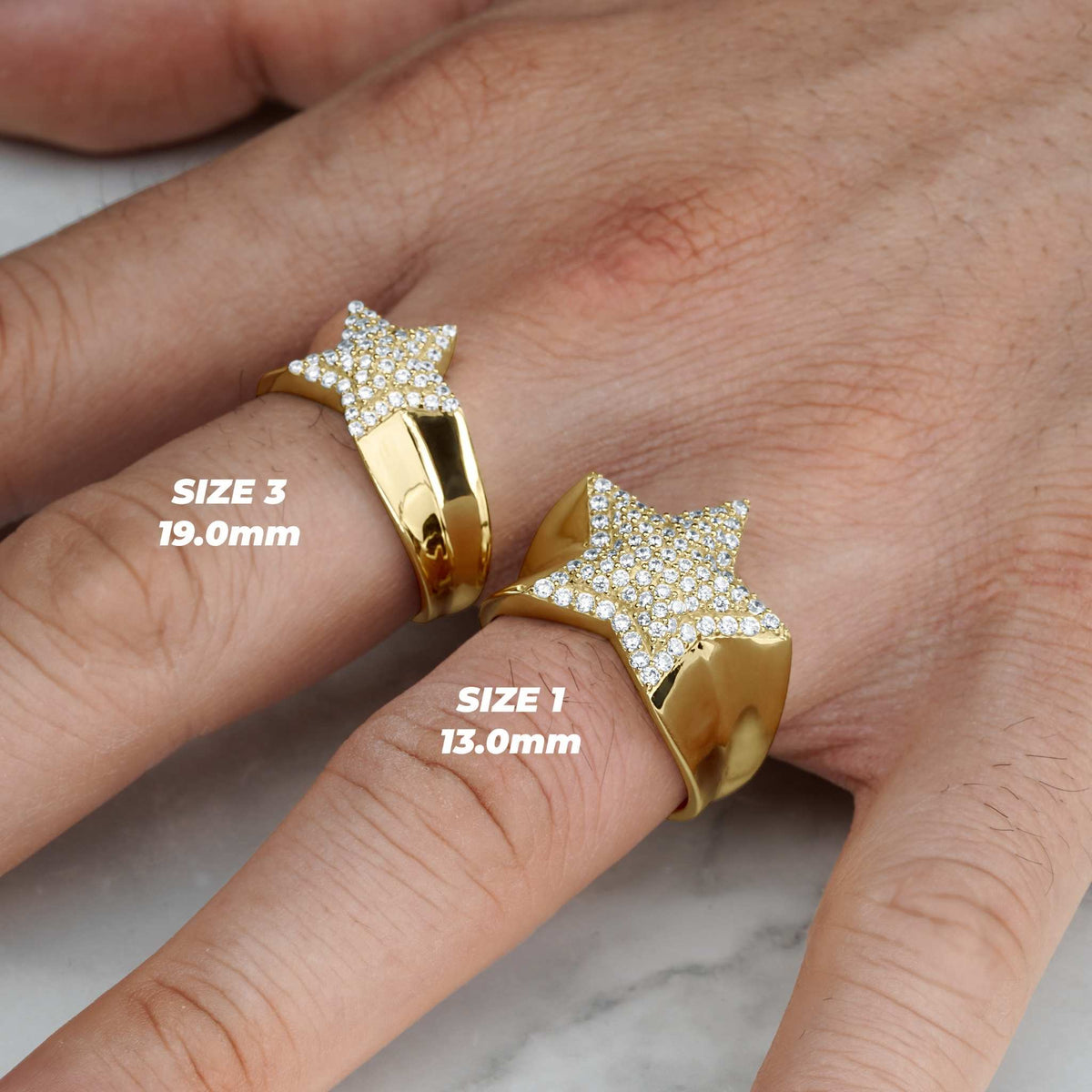 10k - 14k gold iced star rings in Size 1 and Size 3 on a hand.