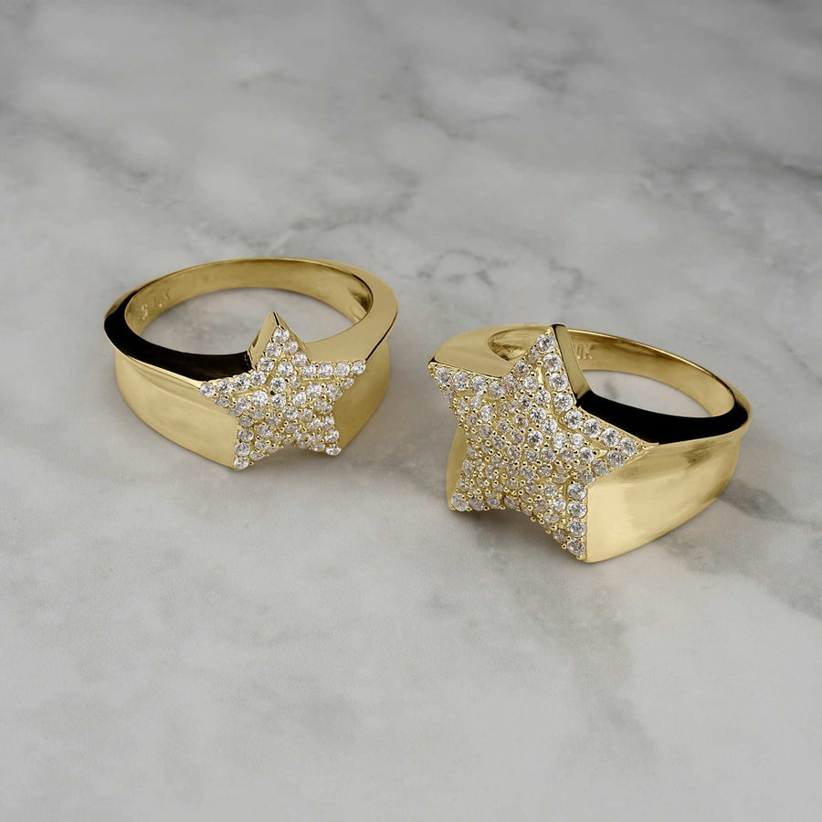 Two gold star-shaped rings encrusted with shimmering cubic zirconia on marble.