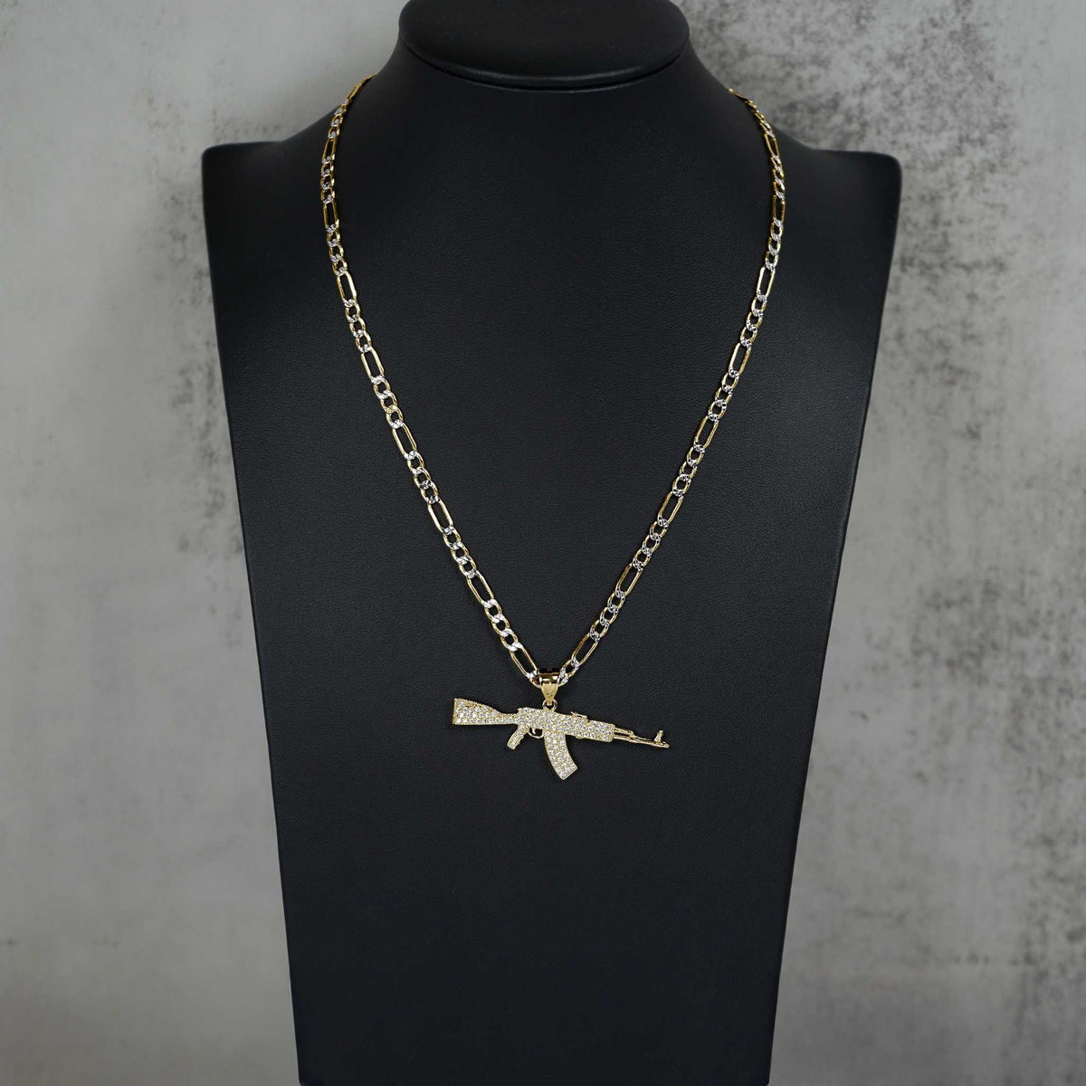 Product display of the gold AK-47 gun pendant necklace on a black bust.