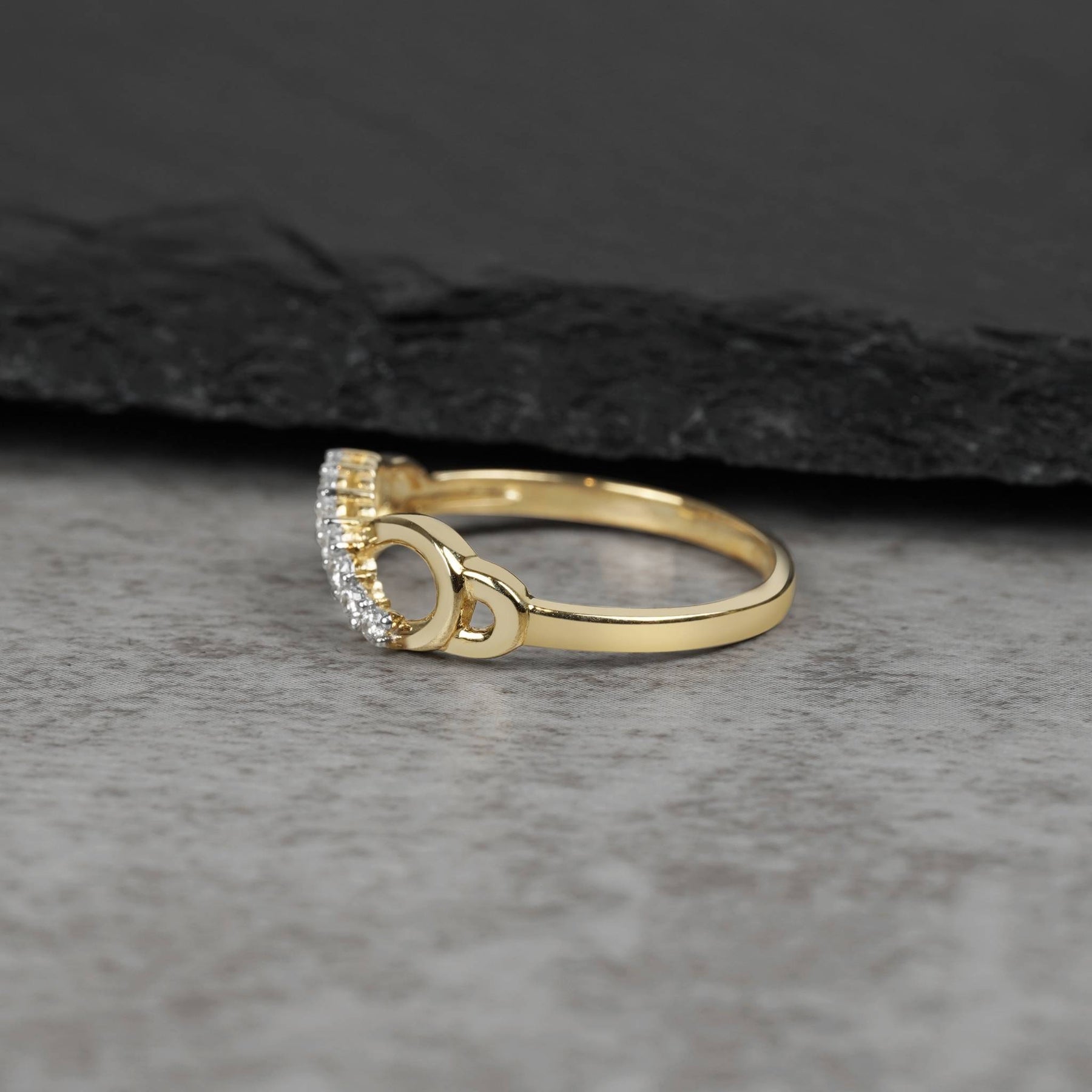 Side view of a gold infinity ring showcasing curved cubic zirconia stone settings
