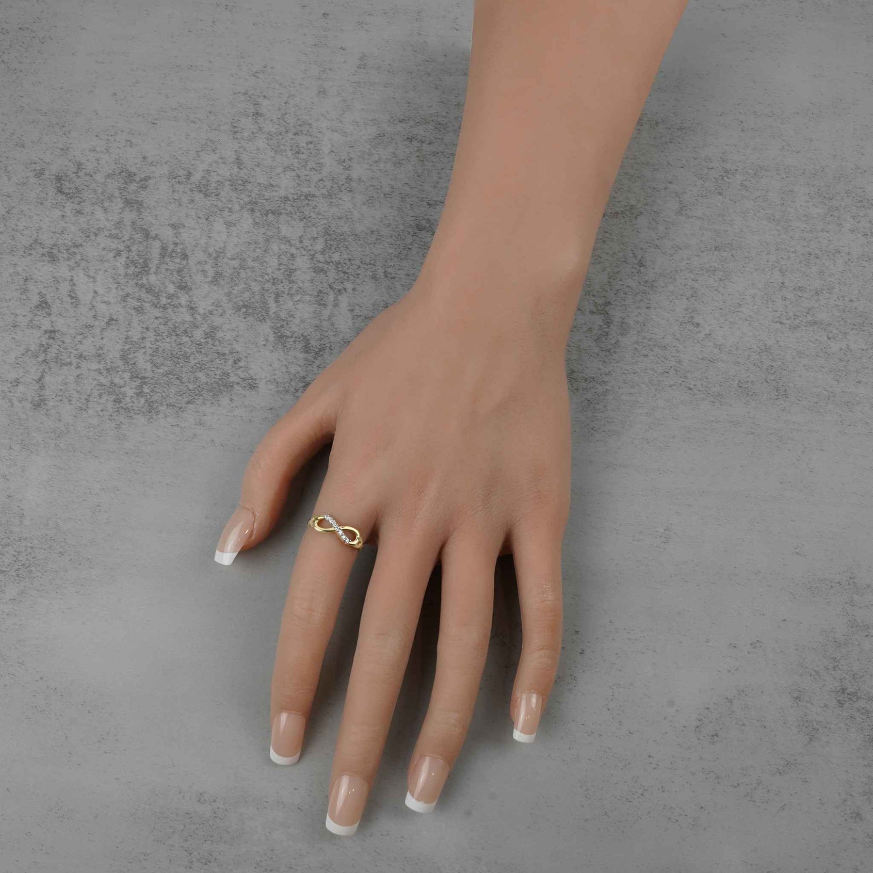 A woman’s hand wearing a gold infinity ring with clear cubic zirconia stones