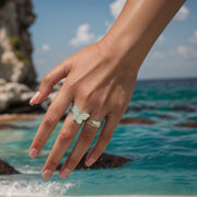 Model wearing a sparkling gold butterfly statement ring outdoors against a scenic ocean backdrop.