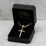 Gold CZ cross pendant necklace presented inside a black jewelry box on marble background.
