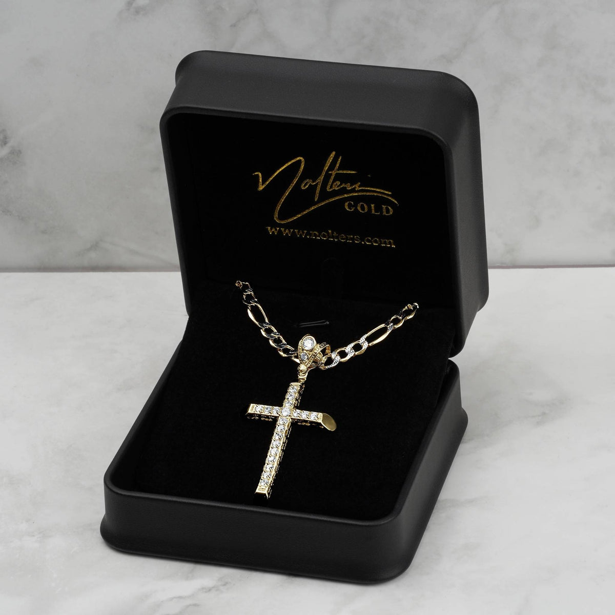 Gold CZ cross pendant necklace presented inside a black jewelry box on marble background.