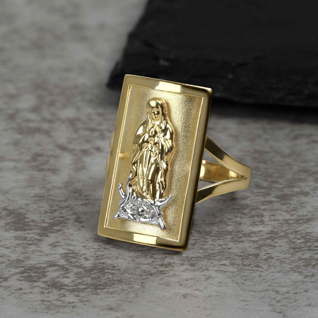 Rectangular two-tone gold ring featuring a detailed Virgin Mary engraving on a gray surface
