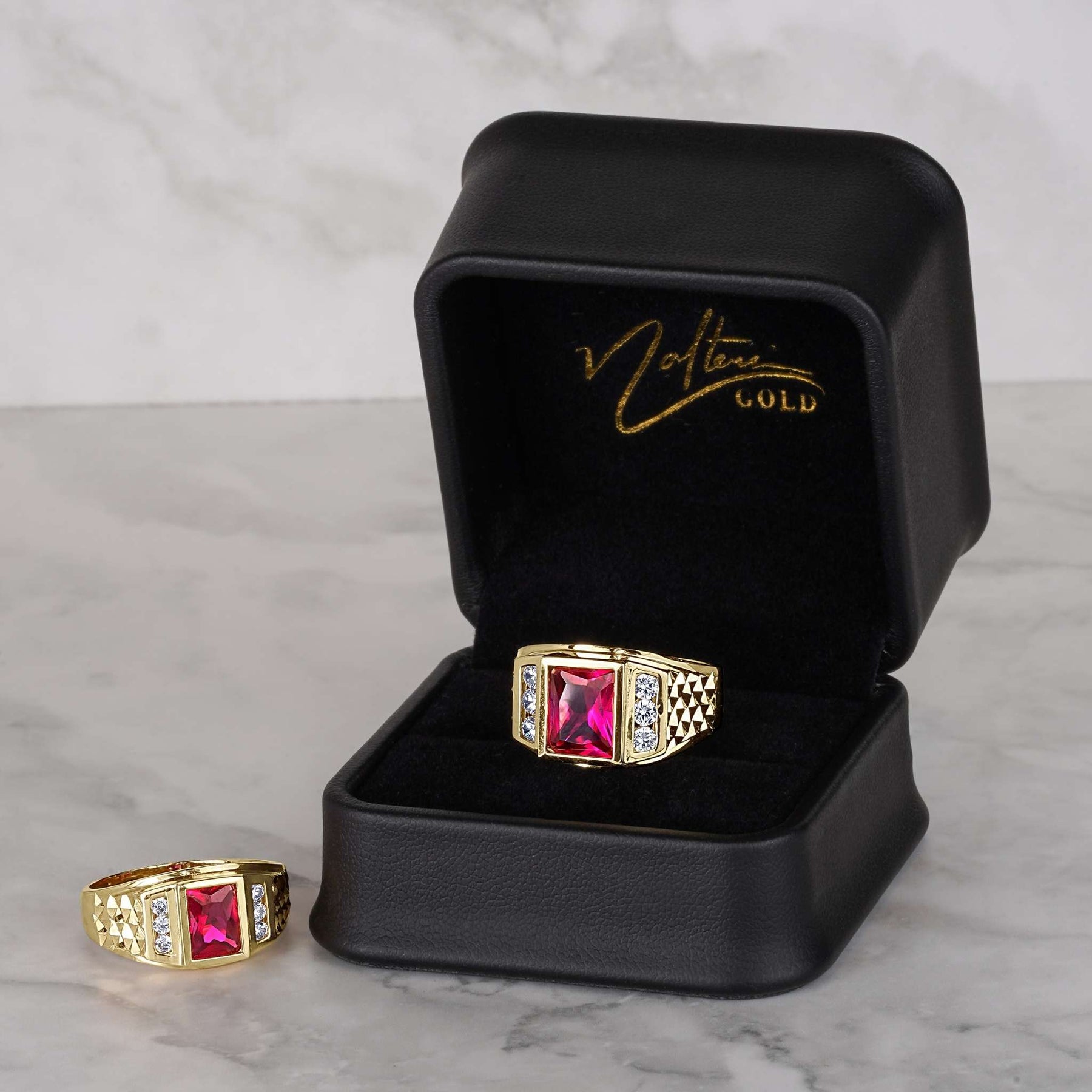 Luxury black Nolters jewelry box showcasing two gold rectangle ruby-colored rings on marble.