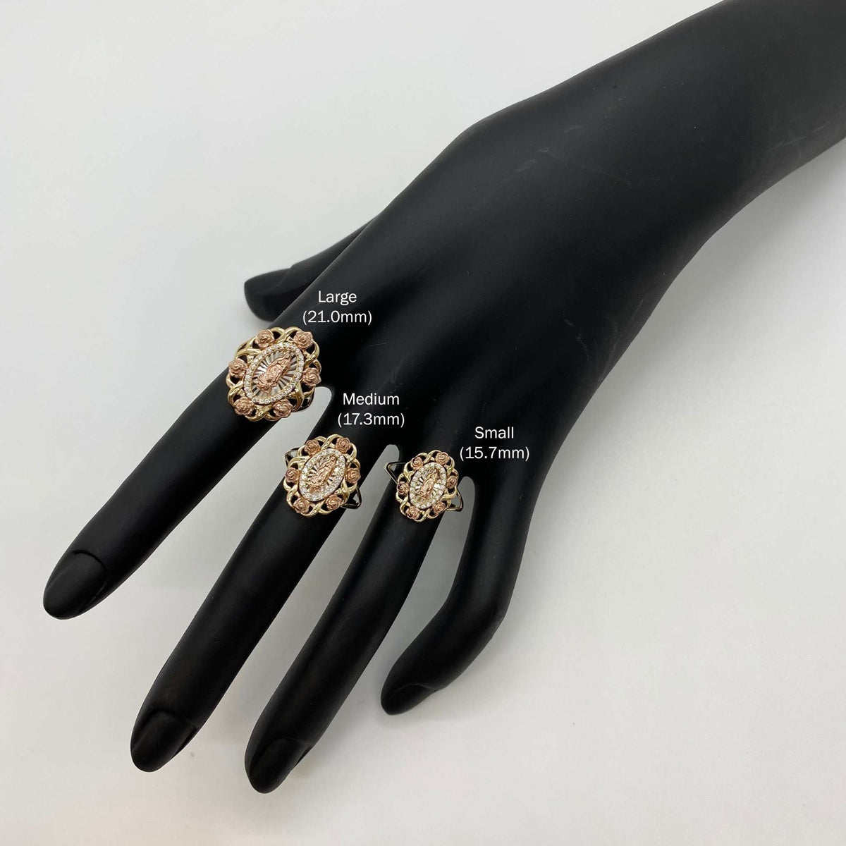 Three 10k - 14k gold Virgin Mary Guadalupe rings on a black mannequin hand.