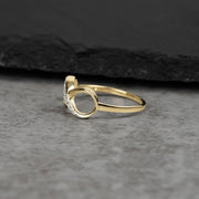 Polished gold infinity band featuring sparkling cubic zirconia crystals on a textured gray surface.