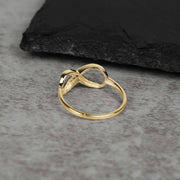 Solid gold Meir infinity band showing side profile and undercarriage on textured slate.