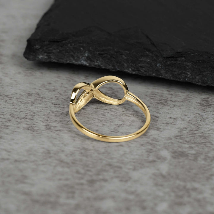 Solid gold Meir infinity band showing side profile and undercarriage on textured slate.
