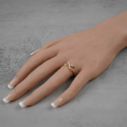 Model hand showcasing a polished gold infinity band accented with cubic zirconia gemstones.