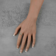 Yellow gold infinity ring on a mannequin hand with a french manicure.