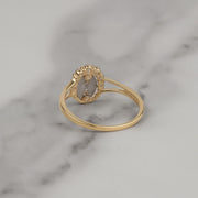 Back view of a gold Virgin Mary ring resting on white marble.