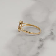 Side profile of a gold Virgin Mary ring resting on white marble
