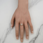 Top-down view of a gold Virgin Mary ring worn over white marble.