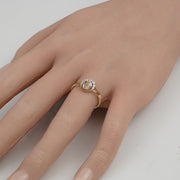 Dainty gold Virgin Mary ring worn on a finger against a plain background.