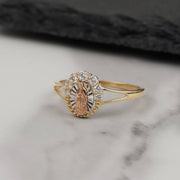 Gold Virgin Mary medallion ring with a clear stone halo on white marble.