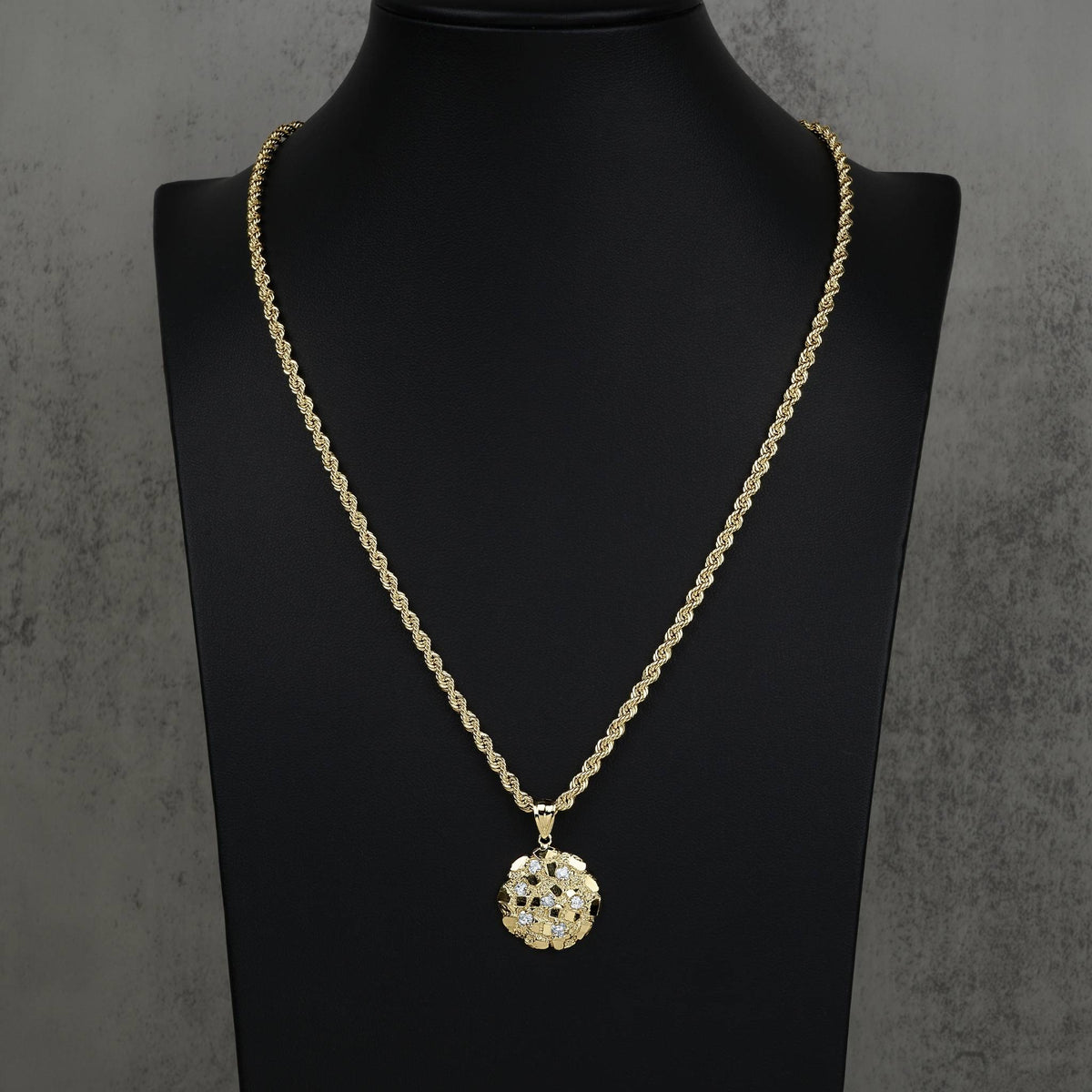 Textured gold round pendant and rope chain necklace displayed on a black mannequin.