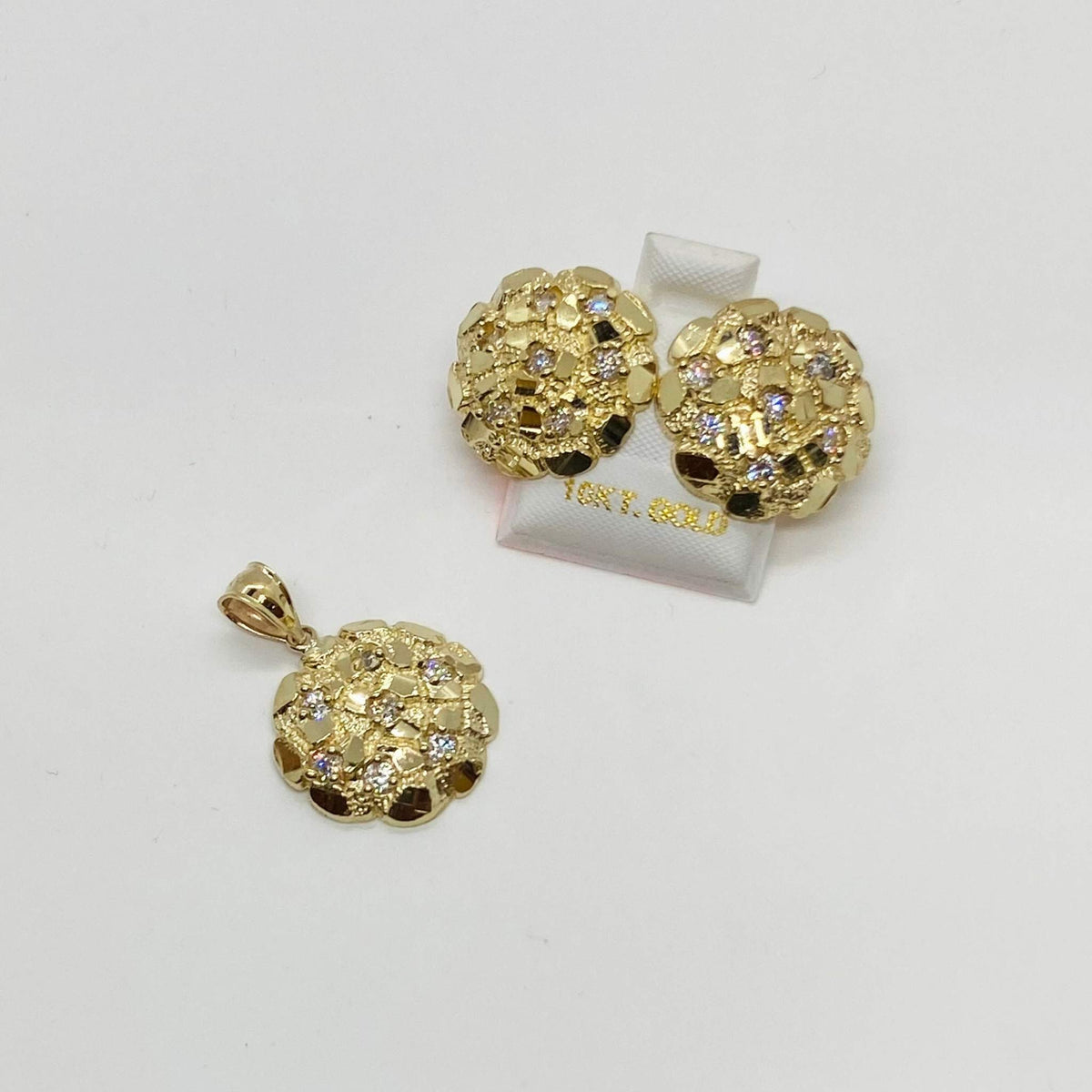 Gold nugget round cubic zirconia stud earrings displayed next to a matching pendant.