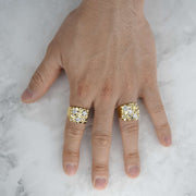 Two bold, textured yellow gold nugget rings with glittering gemstone accents displayed on a hand.
