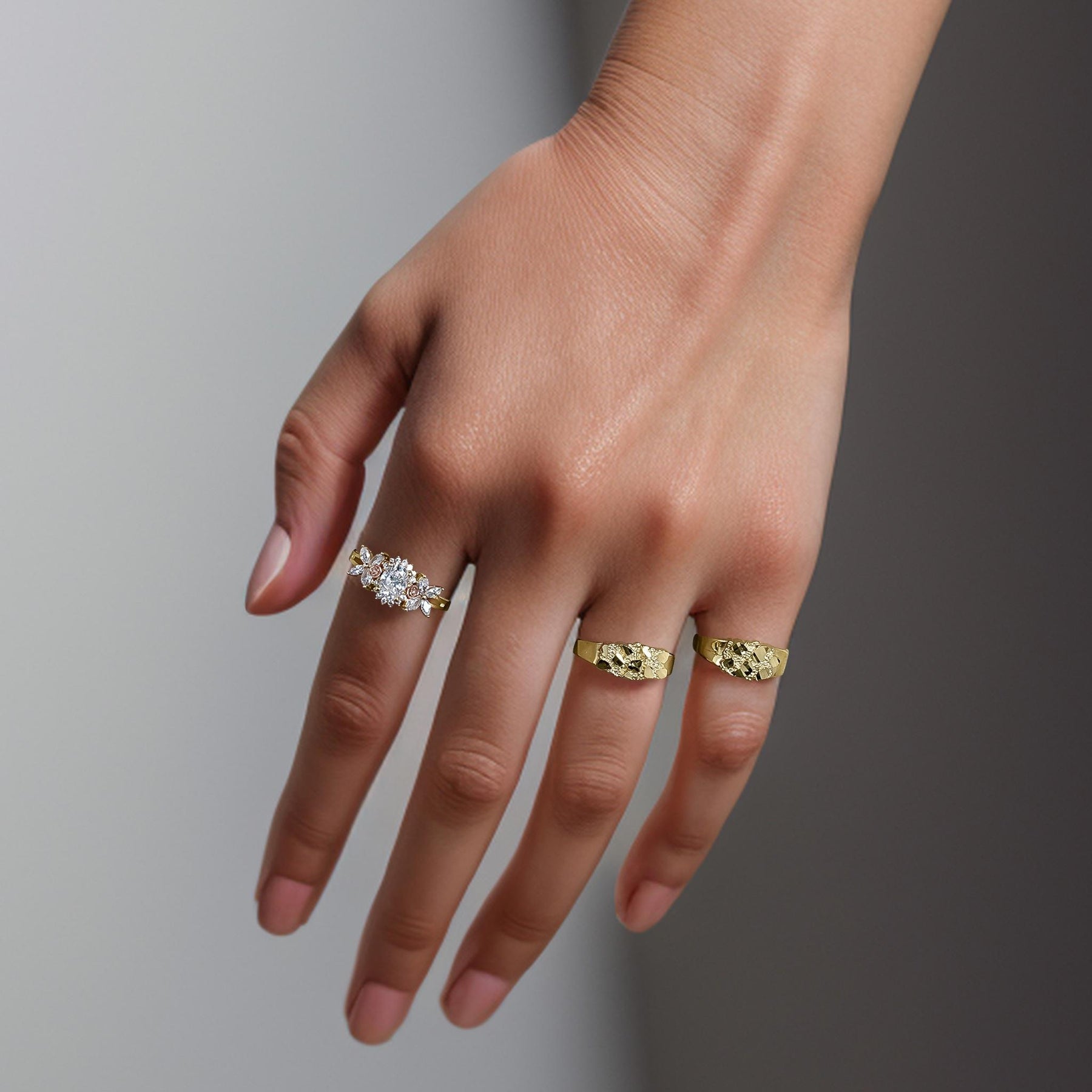 Lifestyle view of textured yellow gold Oli nugget band rings worn on a hand.