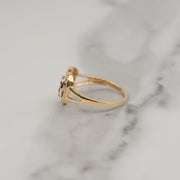 Side view of a gold Virgin Mary heart ring resting on white marble.