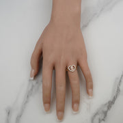 Top-down view of a hand wearing a gold Virgin Mary heart ring on marble.