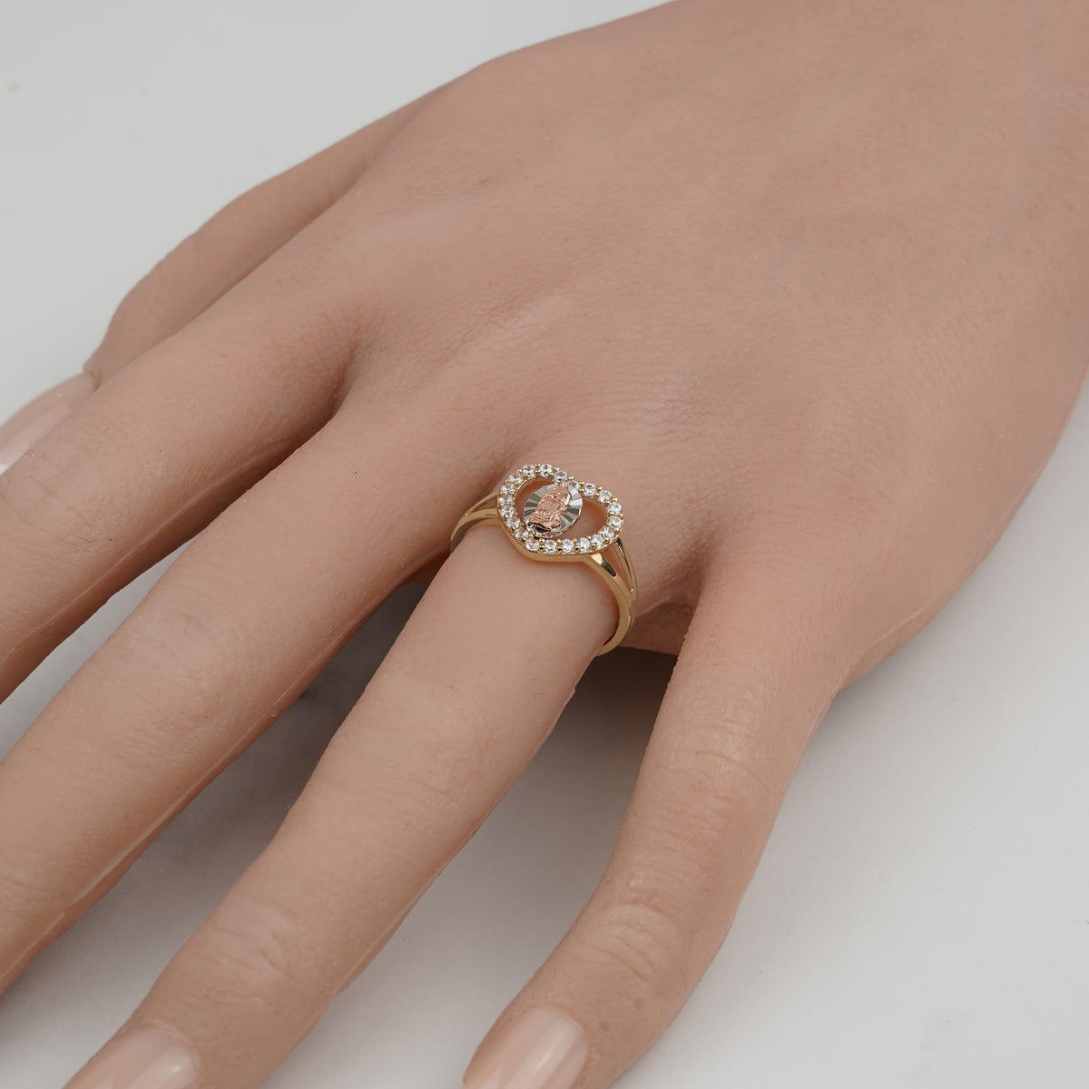 Gold Virgin Mary heart ring worn on a hand, featuring cubic zirconia accents.