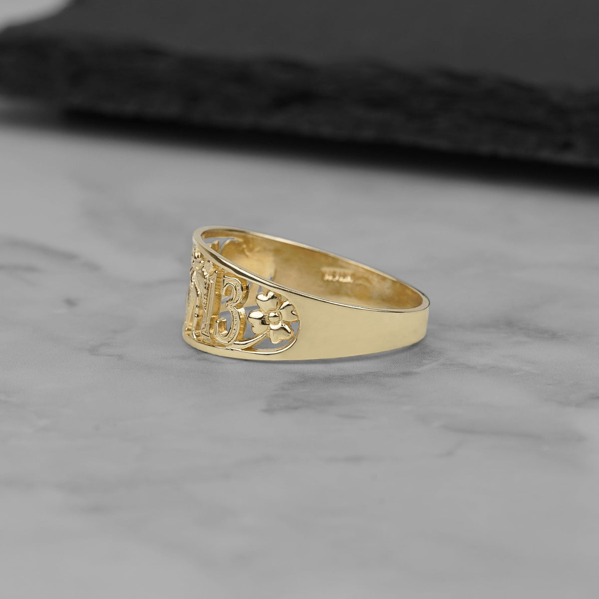 Side profile view of the intricate yellow gold cut-out lucky motif ring.