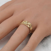Close-up of the intricate yellow gold lucky motif ring worn on a hand.