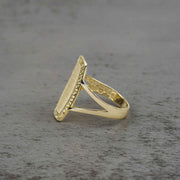 10k - 14k gold oval ring with textured design side view on a gray surface