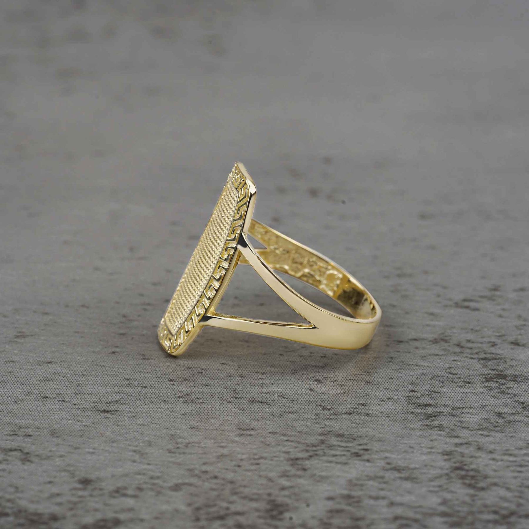 10k - 14k gold oval ring with textured design side view on a gray surface