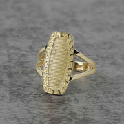 10k - 14k Gold oval ring with intricate design on a gray textured background