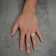 Top-down view of a male hand wearing a two-tone gold praying hands statement ring.