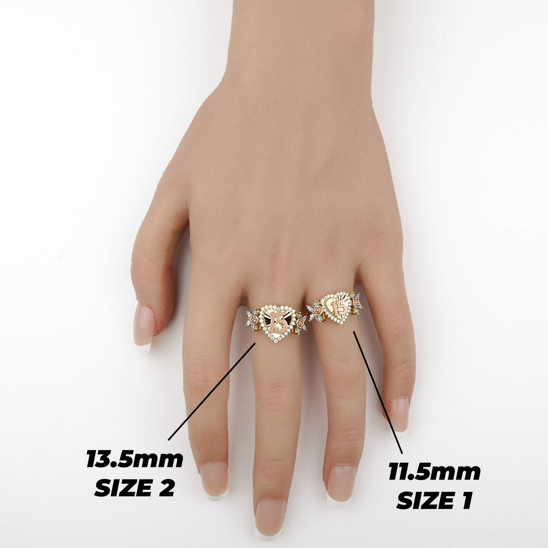 Hand wearing two gold heart Quinceañera rings showing Size 1 and Size 2 comparison.