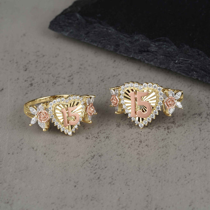 Two sizes of the gold two-tone Blingin heart Quinceañera ring on gray surface.