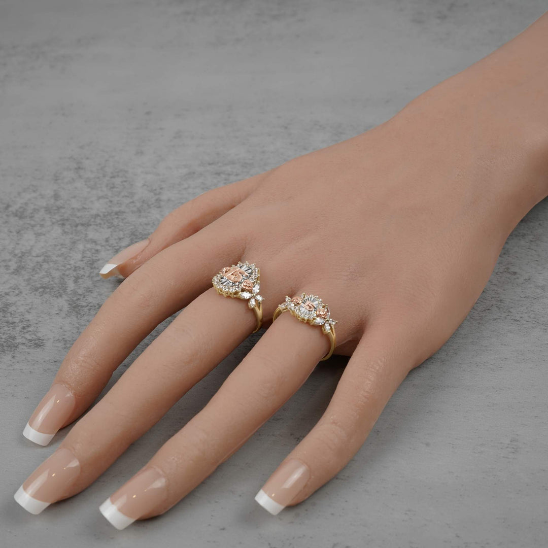 Hand wearing two 10k - 14k gold rings with floral designs on a gray background