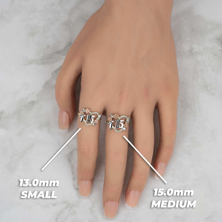 Two tri-color Quinceañera heart rings with size labels worn on a model's hand.