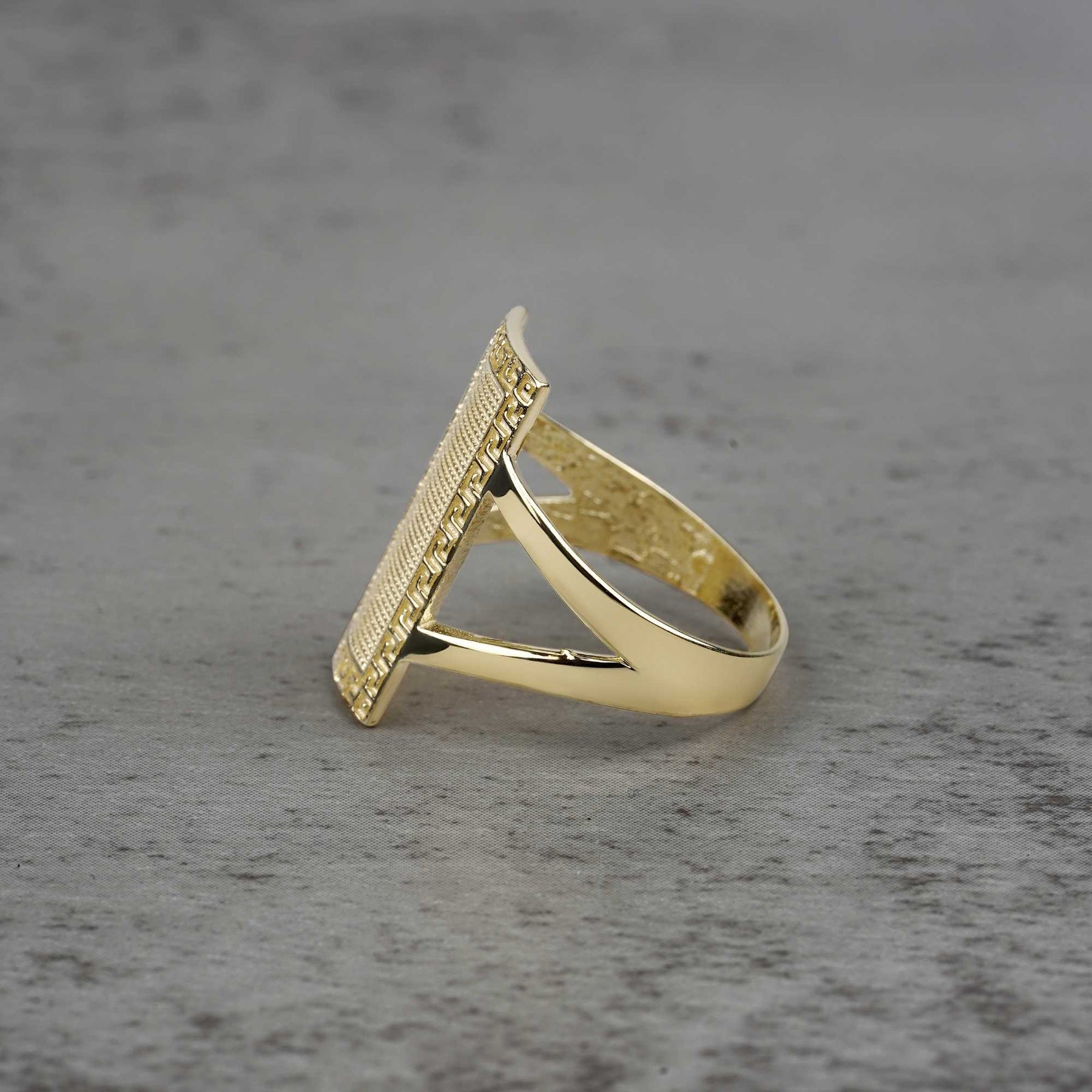 10k - 14k Gold ring with rectangular design sideview on a gray surface