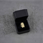 10k - 14k rectangular gold ring in a black jewelry box on a gray surface