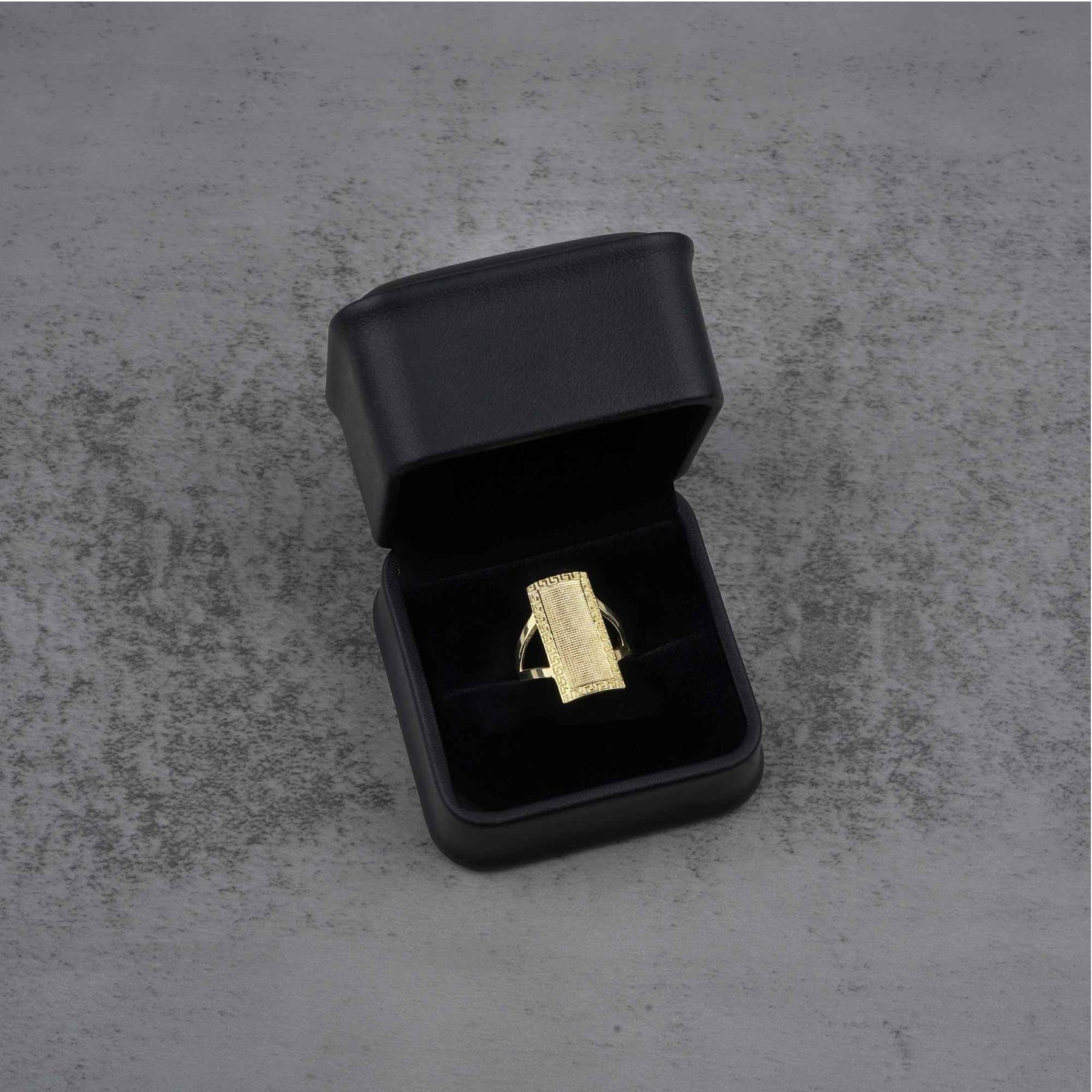 10k - 14k rectangular gold ring in a black jewelry box on a gray surface