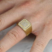 Gold square signet ring with glittering cubic zirconia worn on a person's hand.