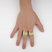 Hand wearing two 10k - 14k gold Rexo Centenario rings on a white background