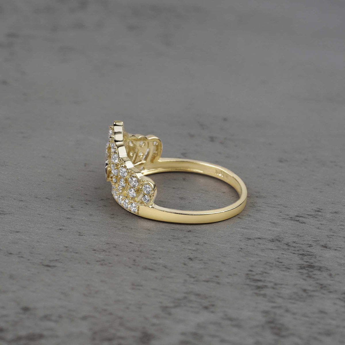 10k - 14k gold ring with cubic zirconia accents side view on a gray surface