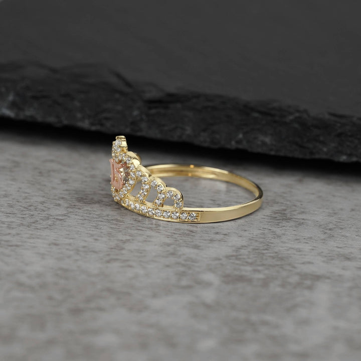 Side profile of a gold royal crown ring with CZ crystals on dark stone.
