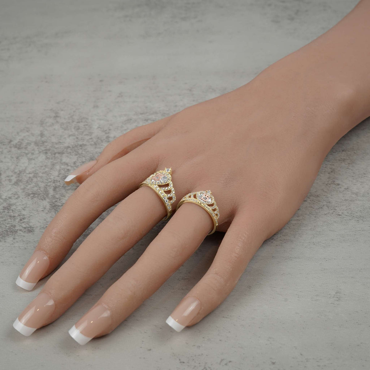 14k gold royal quinceanera crown rings with cubic zirconia modeled on a hand.