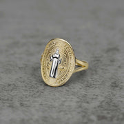 10K–14K oval gold ring with a white gold Saint Benedict design on a gray surface