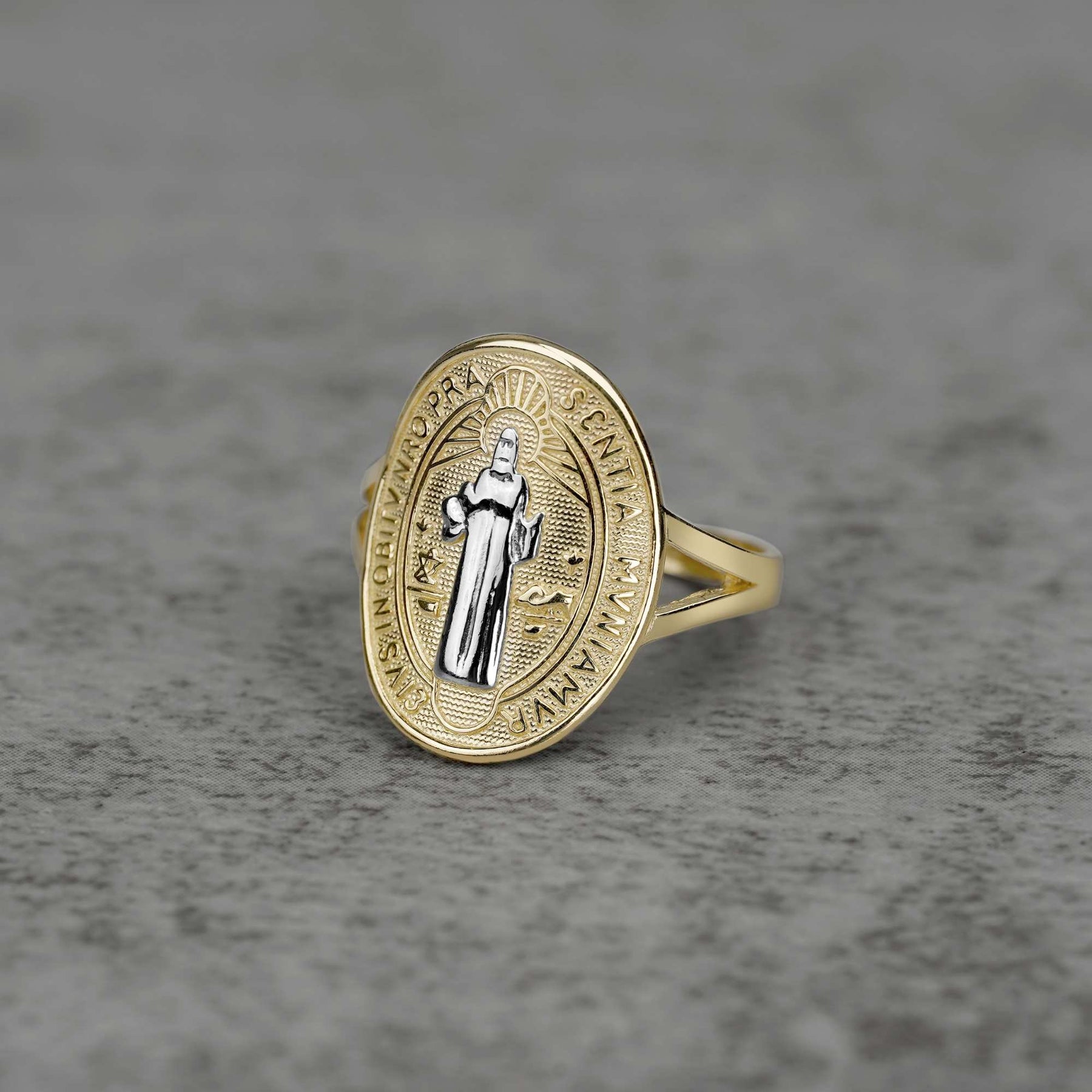 10K–14K oval gold ring with a white gold Saint Benedict design on a gray surface