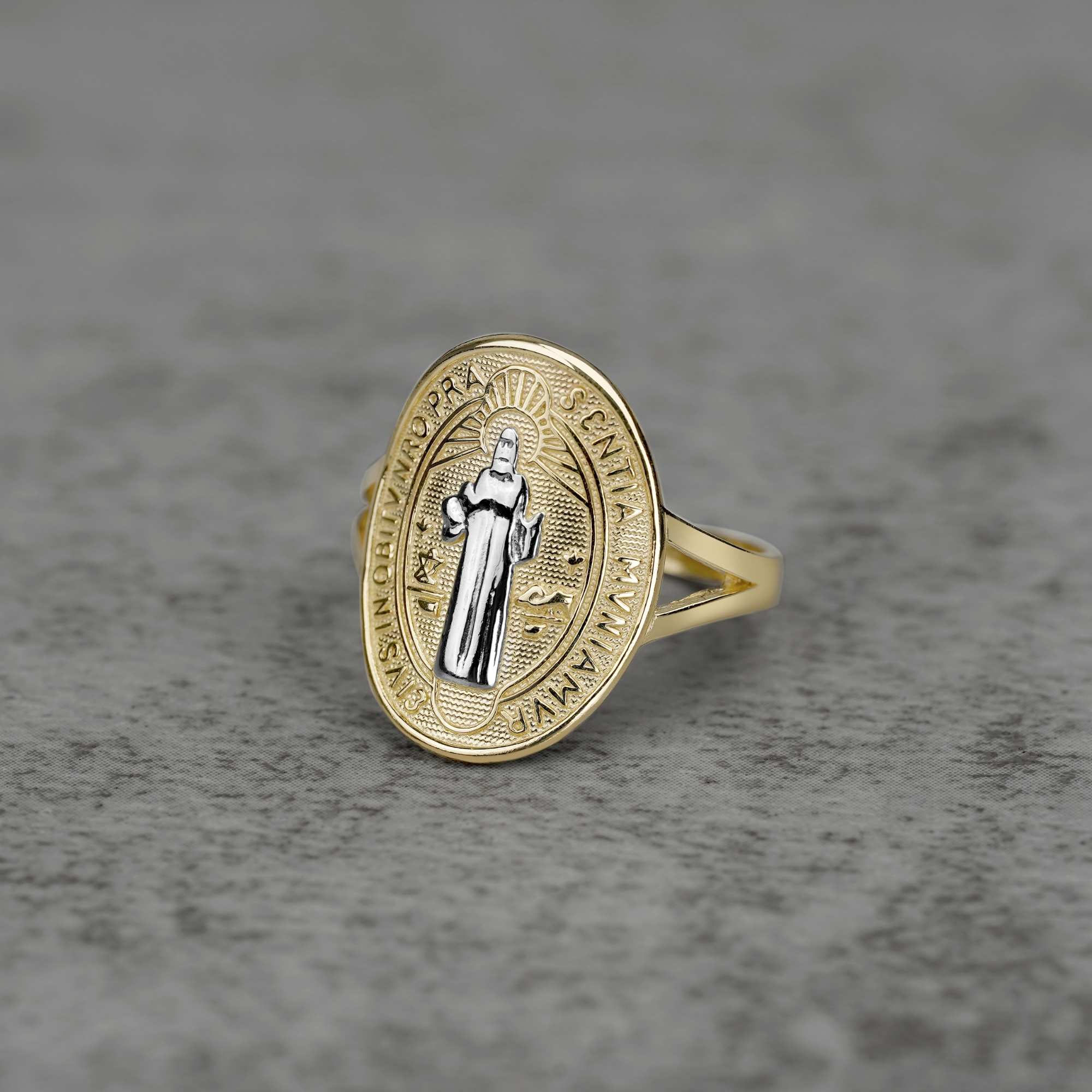 10K–14K oval gold ring with a white gold Saint Benedict design on a gray surface