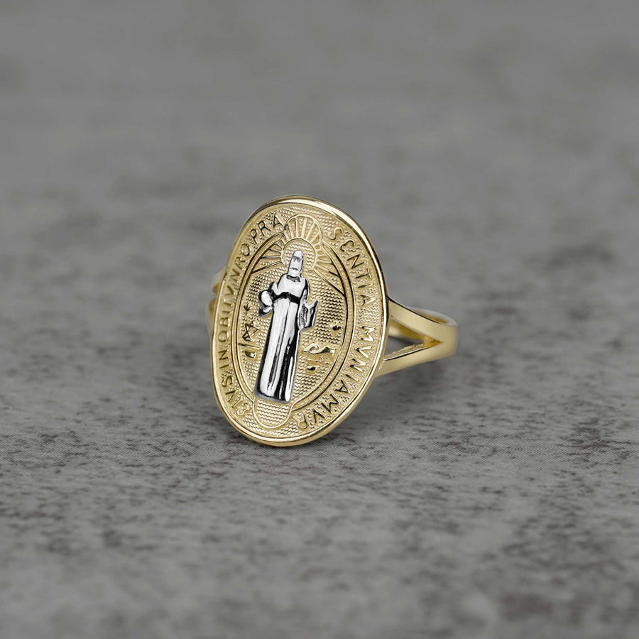 10K–14K oval gold ring with a white gold Saint Benedict design on a gray surface